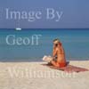 GW12470-50 = Young lady (with mobile and financial newspaper) on the beach at Platja de Trenc (formerly Es Trenc ), SW Mallorca, Baleares, Spain.