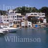 GW29655-60 = View looking North - with motor dinghy entering marina, moored sailing yachts, colourful boat houses, and marina side apartment blocks - near sea entrance to Cala D'Or Marina, Cala D'Or, Santanyi, South East Mallorca, Balearic Islands, Spain. 7th July 2007.