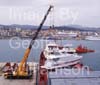 GW32215-60 = Prepare for lift off - Johnson 105 luxury motor yacht / superyacht awaiting discharge from container vessel "OPDR Tanger" with two heavy lift cranes and tugboat in attendance, in the Port of Palma de Mallorca, Balearic Islands, Spain. 7th April 2008.