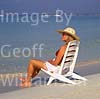 GW16260 = Scene on Es Trenc beach ( Platja de Trenc) in SE Mallorca ( girl in straw hat and bikini sitting on beach chair by waters edge ), Baleares, Spain. 21st September 2003. Model Release. 